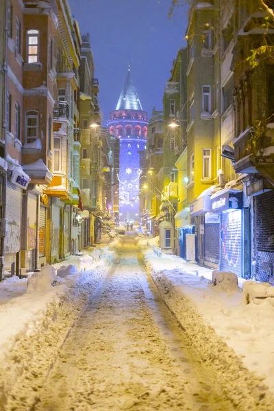  İstanbul 'da kış. Dar bir sokaktan tarihi Galata Kulesi manzarası ve karlı hava.