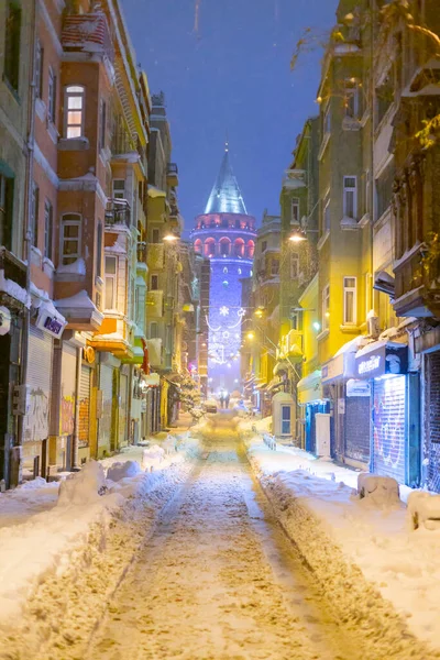  İstanbul 'da kış. Dar bir sokaktan tarihi Galata Kulesi manzarası ve karlı hava.