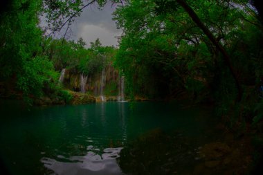 Türkiye 'nin Antalya kentindeki Kursunlu kentindeki sakin şelaleye üçlülerin arasından bakan bir fotoğraf.