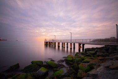 Uzun pozlama görüntü dramatik günbatımı veya gündoğumu, gökyüzü ve bulutlar üzerinde tropikal deniz manzara manzara içinde denize içinde eski küçük İskelesi