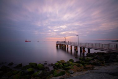 Uzun pozlama görüntü dramatik günbatımı veya gündoğumu, gökyüzü ve bulutlar üzerinde tropikal deniz manzara manzara içinde denize içinde eski küçük İskelesi