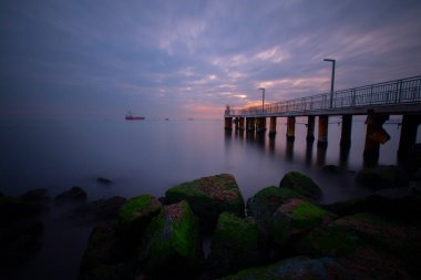 Uzun pozlama görüntü dramatik günbatımı veya gündoğumu, gökyüzü ve bulutlar üzerinde tropikal deniz manzara manzara içinde denize içinde eski küçük İskelesi