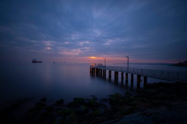 Uzun pozlama görüntü dramatik günbatımı veya gündoğumu, gökyüzü ve bulutlar üzerinde tropikal deniz manzara manzara içinde denize içinde eski küçük İskelesi