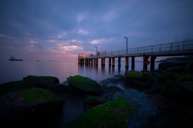 Uzun pozlama görüntü dramatik günbatımı veya gündoğumu, gökyüzü ve bulutlar üzerinde tropikal deniz manzara manzara içinde denize içinde eski küçük İskelesi
