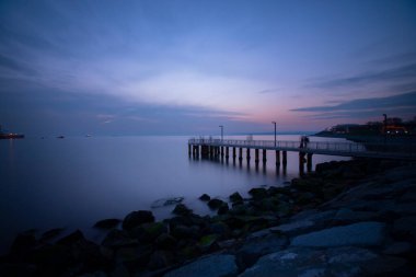 Uzun pozlama görüntü dramatik günbatımı veya gündoğumu, gökyüzü ve bulutlar üzerinde tropikal deniz manzara manzara içinde denize içinde eski küçük İskelesi