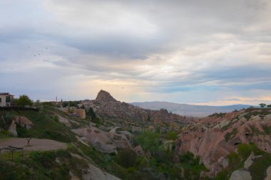 Türkiye 'nin Kapadokya bölgesindeki Uchisar' da bir bahar günü Güvercin Vadisi 'nin yukarısında bir tabela direğinde bir güvercin oturuyor.