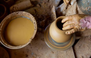 Çömlekçi çarkında çalışan kadınlar. Eller kilden bir kap yontuyor. Çömlekçi çarkında modellik üzerine atölye.