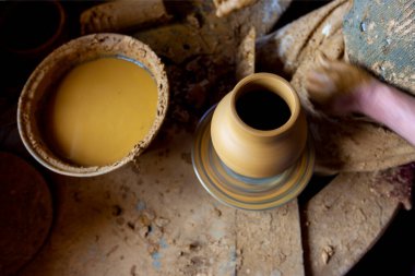 Çömlekçi çarkında çalışan kadınlar. Eller kilden bir kap yontuyor. Çömlekçi çarkında modellik üzerine atölye.