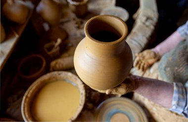 Çömlekçi çarkında çalışan kadınlar. Eller kilden bir kap yontuyor. Çömlekçi çarkında modellik üzerine atölye.