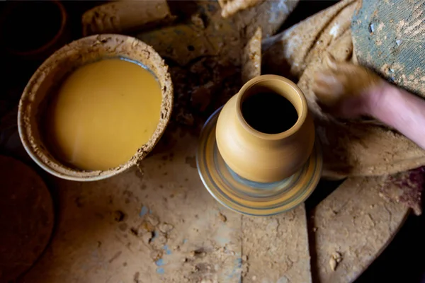 Çömlekçi çarkında çalışan kadınlar. Eller kilden bir kap yontuyor. Çömlekçi çarkında modellik üzerine atölye.