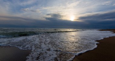 An empty sandy beach in Antalya, Lara, Kundu and visible mountains above the sea line, Mediterranean sea, stones.