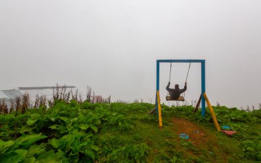 Uçurumun kenarında sallan, insanlar manzaraya karşı sallanıyor.