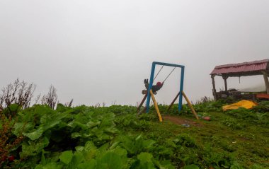 Uçurumun kenarında sallan, insanlar manzaraya karşı sallanıyor.