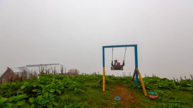 Uçurumun kenarında sallan, insanlar manzaraya karşı sallanıyor.