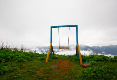 Uçurumun kenarında sallan, insanlar manzaraya karşı sallanıyor.