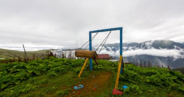 Uçurumun kenarında sallan, insanlar manzaraya karşı sallanıyor.