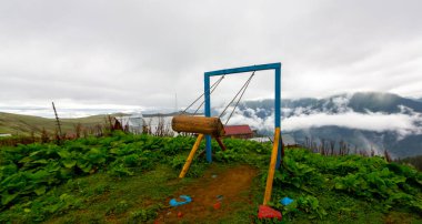 Uçurumun kenarında sallan, insanlar manzaraya karşı sallanıyor.