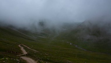İsviçre 'deki Greene Platosu' nda sisli bir günde bahar sonlarında dağların arasında dolambaçlı bir dağ yolu ve yaylalar. yüksek kaliteli fotoğraf