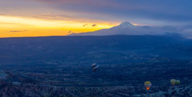 Kayseri 'deki volkanik erciyeler dağı güneş doğarken etrafında uçan kapadokya balonları.