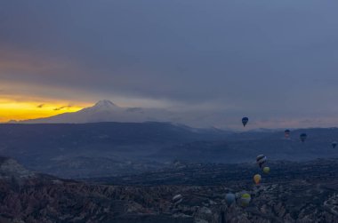 Kayseri 'deki volkanik erciyeler dağı güneş doğarken etrafında uçan kapadokya balonları.