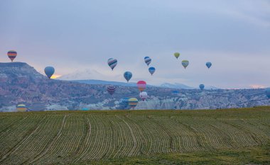 Kayseri 'deki volkanik erciyeler dağı güneş doğarken etrafında uçan kapadokya balonları.