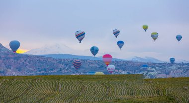 Kayseri 'deki volkanik erciyeler dağı güneş doğarken etrafında uçan kapadokya balonları.