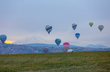 Kayseri 'deki volkanik erciyeler dağı güneş doğarken etrafında uçan kapadokya balonları.