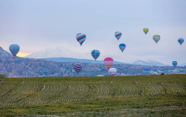 Kayseri 'deki volkanik erciyeler dağı güneş doğarken etrafında uçan kapadokya balonları.