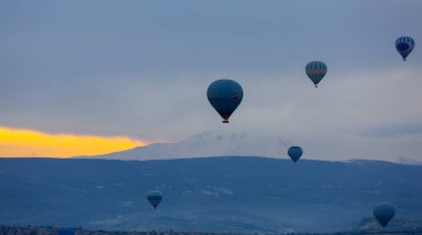 Kayseri 'deki volkanik erciyeler dağı güneş doğarken etrafında uçan kapadokya balonları.