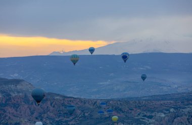 Kayseri 'deki volkanik erciyeler dağı güneş doğarken etrafında uçan kapadokya balonları.