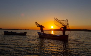 Balıkçılar göle ağ atıyorlar.