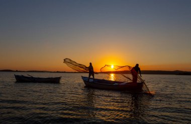Balıkçılar göle ağ atıyorlar.
