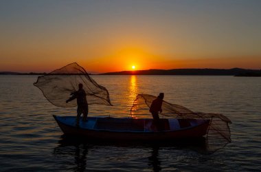 Balıkçılar göle ağ atıyorlar.