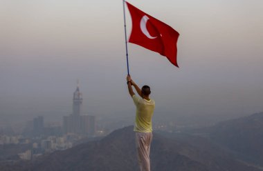 Türkçe bayrak sallıyor, zam kulesi arkada.