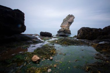 Deniz kenarındaki büyük kayalar uzun pozlama tekniğiyle açıktır.