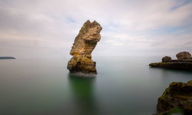 Deniz kenarındaki büyük kayalar uzun pozlama tekniğiyle açıktır.