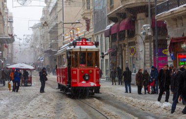 İnsanlar kar altında Istiklal Caddesi 'nde yürürken aynı zamanda tarihi kırmızı tramvay yoluna çıkıyor..