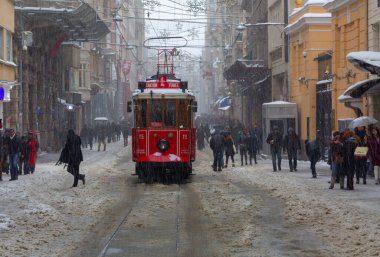 İnsanlar kar altında Istiklal Caddesi 'nde yürürken aynı zamanda tarihi kırmızı tramvay yoluna çıkıyor..