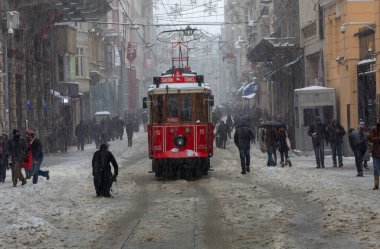 İnsanlar kar altında Istiklal Caddesi 'nde yürürken aynı zamanda tarihi kırmızı tramvay yoluna çıkıyor..