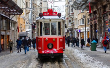 İnsanlar kar altında Istiklal Caddesi 'nde yürürken aynı zamanda tarihi kırmızı tramvay yoluna çıkıyor..