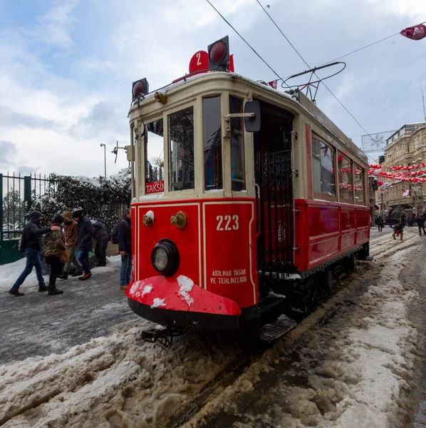 雪の下でイスタリックストリートを歩く人々と同時に その途中で歴史的な赤いトラム — ストック写真