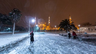 Kış günü İstanbul, Türkiye 'de kar yağan mavi cami (Sultanahmet Camii). Yerel halk Türkiye 'nin simgelerinde yürüyor.