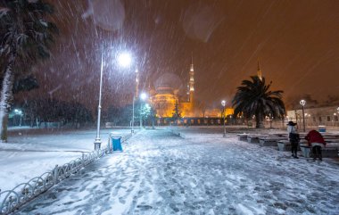 Kış günü İstanbul, Türkiye 'de kar yağan mavi cami (Sultanahmet Camii). Yerel halk Türkiye 'nin simgelerinde yürüyor.