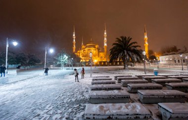 Kış günü İstanbul, Türkiye 'de kar yağan mavi cami (Sultanahmet Camii). Yerel halk Türkiye 'nin simgelerinde yürüyor.