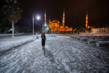 Kış günü İstanbul, Türkiye 'de kar yağan mavi cami (Sultanahmet Camii). Yerel halk Türkiye 'nin simgelerinde yürüyor.
