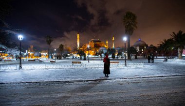 Kış günü İstanbul, Türkiye 'de kar yağan mavi cami (Sultanahmet Camii). Yerel halk Türkiye 'nin simgelerinde yürüyor.