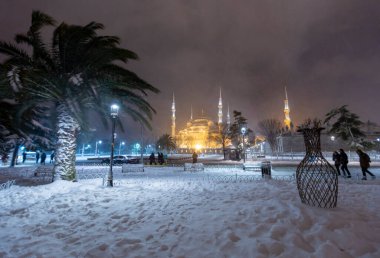 Kış günü İstanbul, Türkiye 'de kar yağan mavi cami (Sultanahmet Camii). Yerel halk Türkiye 'nin simgelerinde yürüyor.
