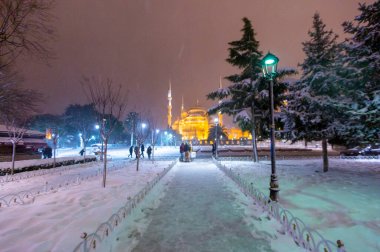 Kış günü İstanbul, Türkiye 'de kar yağan mavi cami (Sultanahmet Camii). Yerel halk Türkiye 'nin simgelerinde yürüyor.