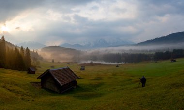 Orman kenarında dağ çayırında küçük bir kulübe, Geroldsee arka planda Karwendel Dağları gündoğumunda, Kaltenbrunn, Yukarı Bavyera, Almanya