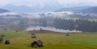 Orman kenarında dağ çayırında küçük bir kulübe, Geroldsee arka planda Karwendel Dağları gündoğumunda, Kaltenbrunn, Yukarı Bavyera, Almanya
